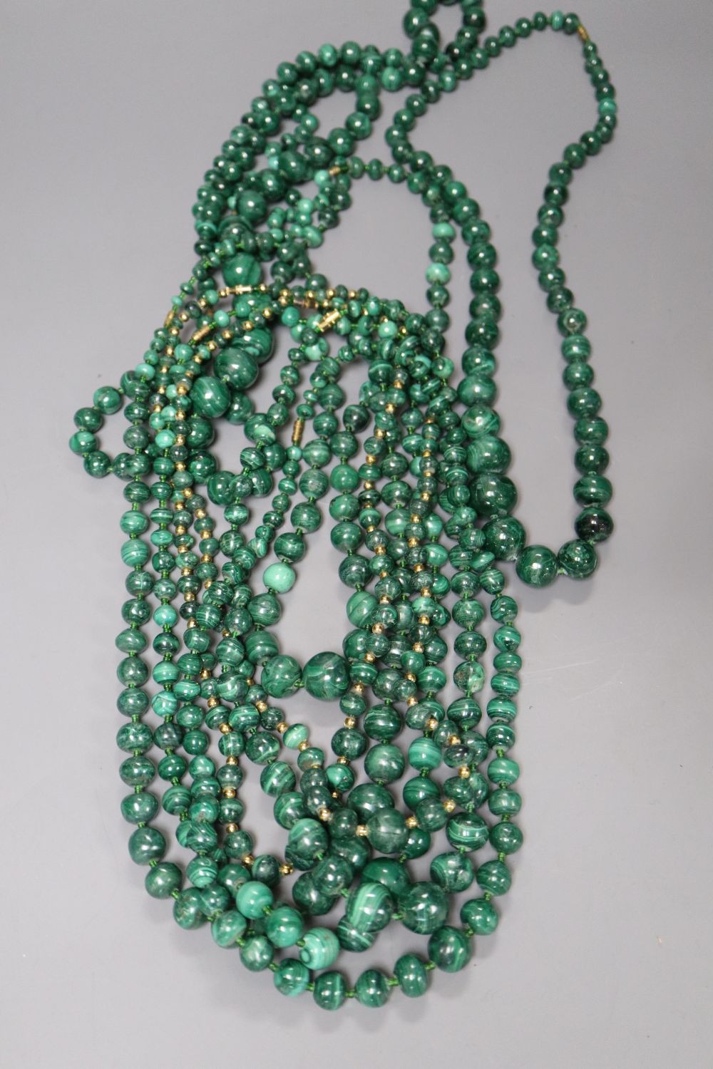 Ten assorted single strand malachite bead necklaces, two with gilt metal spacers, largest approx. 60cm.